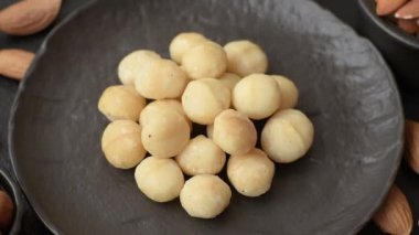 Koyu beton arka planda seramik kasede soyulmuş macadamia cevizi. Besin kaynağı olarak fındık