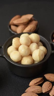 Koyu beton arka planda seramik kasede soyulmuş macadamia cevizi. Besin kaynağı olarak fındık