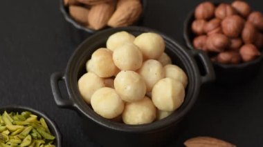 Koyu beton arka planda seramik kasede soyulmuş macadamia cevizi. Besin kaynağı olarak fındık