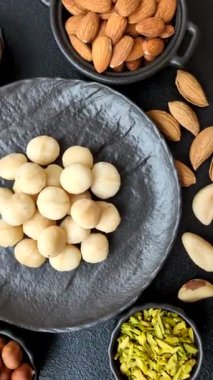 Koyu beton arka planda seramik kasede soyulmuş macadamia cevizi. Besin kaynağı olarak fındık