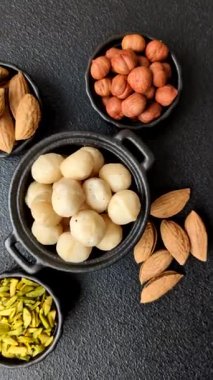 Koyu beton arka planda seramik kasede soyulmuş macadamia cevizi. Besin kaynağı olarak fındık