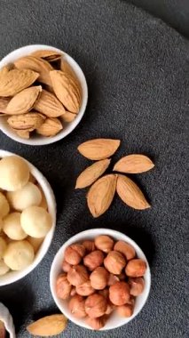 Koyu beton arka planda seramik kasede soyulmuş macadamia cevizi. Besin kaynağı olarak fındık