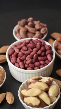 Koyu beton arka planda bir kasede yer fıstığı ya da kabuğu soyulmuş graundnut. Protein kaynağı olarak fındık