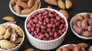 Koyu beton arka planda bir kasede yer fıstığı ya da kabuğu soyulmuş graundnut. Protein kaynağı olarak fındık