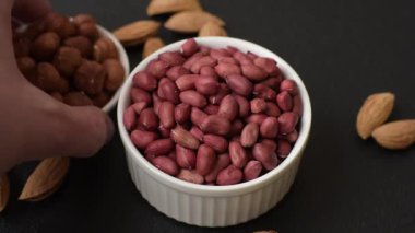 Koyu beton arka planda bir kasede yer fıstığı ya da kabuğu soyulmuş graundnut. Protein kaynağı olarak fındık