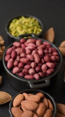 Koyu beton arka planda bir kasede yer fıstığı ya da kabuğu soyulmuş graundnut. Protein kaynağı olarak fındık