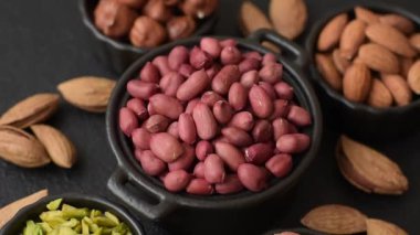 Koyu beton arka planda bir kasede yer fıstığı ya da kabuğu soyulmuş graundnut. Protein kaynağı olarak fındık