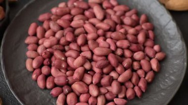 Koyu beton arka planda bir kasede yer fıstığı ya da kabuğu soyulmuş graundnut. Protein kaynağı olarak fındık