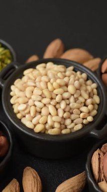 Koyu beton arka planda bir kasede soyulmuş çam fıstığı. Protein kaynağı olarak fındık.