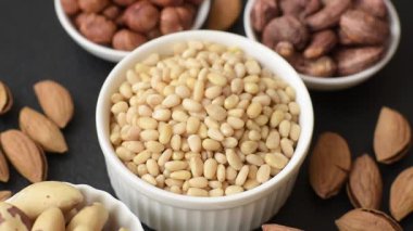 Koyu beton arka planda bir kasede soyulmuş çam fıstığı. Protein kaynağı olarak fındık.