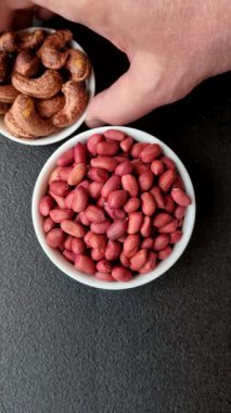 Koyu beton arka planda bir kasede yer fıstığı ya da kabuğu soyulmuş graundnut. Protein kaynağı olarak fındık