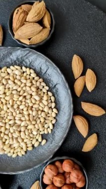 Koyu beton arka planda bir kasede soyulmuş çam fıstığı. Protein kaynağı olarak fındık.