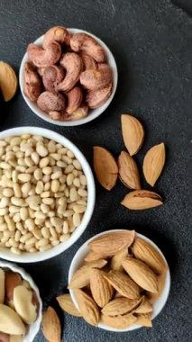 Koyu beton arka planda bir kasede soyulmuş çam fıstığı. Protein kaynağı olarak fındık.