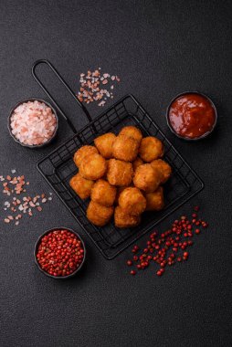 Peynir ya da patates kroketleri, tuzlu ekmekle kızartılmış toplar, koyu beton arka planda baharatlar.