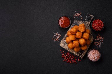 Peynir ya da patates kroketleri, tuzlu ekmekle kızartılmış toplar, koyu beton arka planda baharatlar.