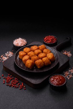 Peynir ya da patates kroketleri, tuzlu ekmekle kızartılmış toplar, koyu beton arka planda baharatlar.