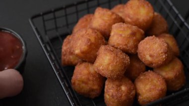 Peynir ya da patates kroketleri, tuzlu ekmekle kızartılmış toplar, koyu beton arka planda baharatlar.