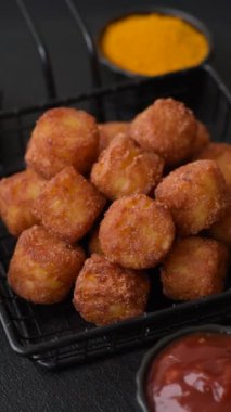 Peynir ya da patates kroketleri, tuzlu ekmekle kızartılmış toplar, koyu beton arka planda baharatlar.