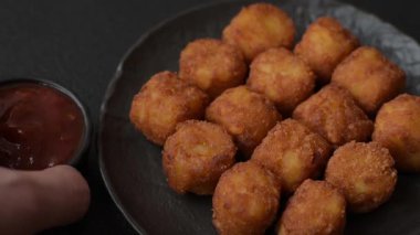 Peynir ya da patates kroketleri, tuzlu ekmekle kızartılmış toplar, koyu beton arka planda baharatlar.