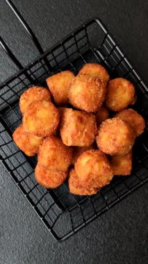 Peynir ya da patates kroketleri, tuzlu ekmekle kızartılmış toplar, koyu beton arka planda baharatlar.