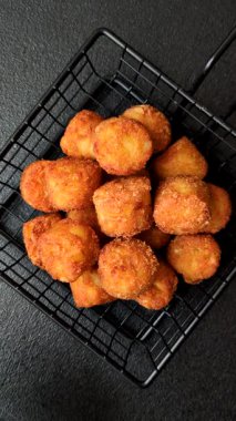 Peynir ya da patates kroketleri, tuzlu ekmekle kızartılmış toplar, koyu beton arka planda baharatlar.