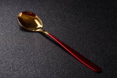 Çelik kaşık ya da kırmızı saplı çay kaşığı koyu beton arka planda. Mutfak aletlerinin bir parçası olarak kaşık