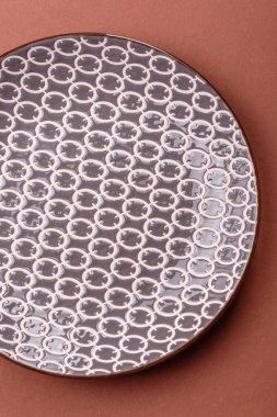 Tek renkli kahverengi arka planda boş seramik plaka. Yemek masasında çatal bıçak takımı olan boş bir tabak.