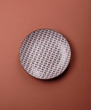 Tek renkli kahverengi arka planda boş seramik plaka. Yemek masasında çatal bıçak takımı olan boş bir tabak.