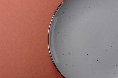 Tek renkli kahverengi arka planda boş seramik plaka. Yemek masasında çatal bıçak takımı olan boş bir tabak.