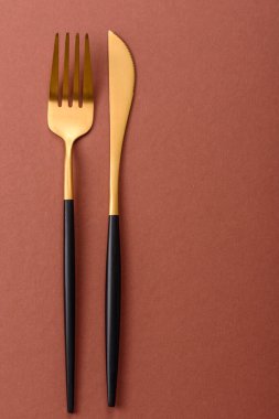 Bıçak ve çatal, kahverengi yemek masasında çatal bıçak takımı. Akşam yemeğini hazırlamak için alet edevat ve çanak çömlek.