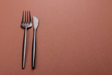 Bıçak ve çatal, kahverengi yemek masasında çatal bıçak takımı. Akşam yemeğini hazırlamak için alet edevat ve çanak çömlek.