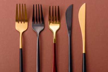 Bıçak ve çatal, kahverengi yemek masasında çatal bıçak takımı. Akşam yemeğini hazırlamak için alet edevat ve çanak çömlek.