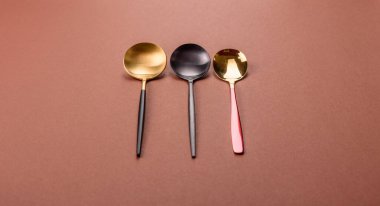 Tek renkli kahverengi arka planda boş metal kaşık. Yemek masasındaki çatal bıçak takımı.