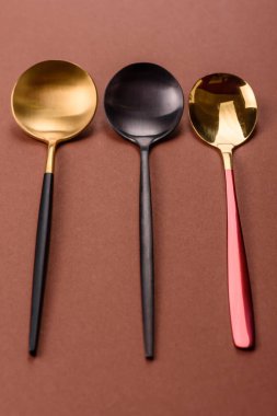 Tek renkli kahverengi arka planda boş metal kaşık. Yemek masasındaki çatal bıçak takımı.