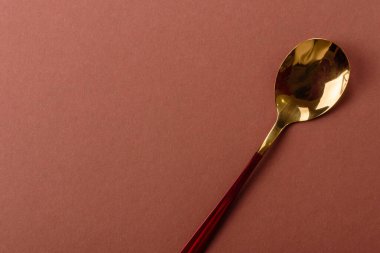 Tek renkli kahverengi arka planda boş metal kaşık. Yemek masasındaki çatal bıçak takımı.