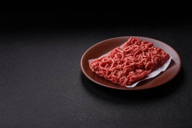 Siyah bir zemin üzerinde tuz ve baharatla doldurulmuş çiğ et ya da domuz eti.