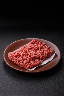 Siyah bir zemin üzerinde tuz ve baharatla doldurulmuş çiğ et ya da domuz eti.