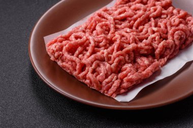 Siyah bir zemin üzerinde tuz ve baharatla doldurulmuş çiğ et ya da domuz eti.