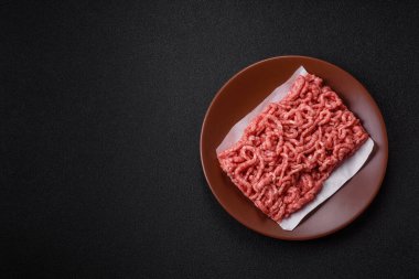 Siyah bir zemin üzerinde tuz ve baharatla doldurulmuş çiğ et ya da domuz eti.