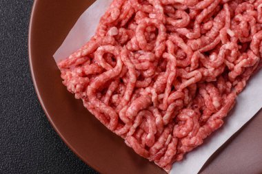 Siyah bir zemin üzerinde tuz ve baharatla doldurulmuş çiğ et ya da domuz eti.