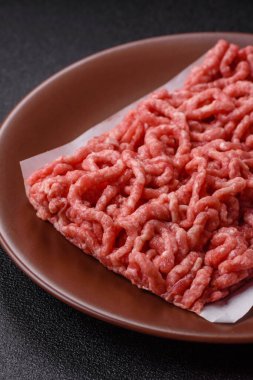 Siyah bir zemin üzerinde tuz ve baharatla doldurulmuş çiğ et ya da domuz eti.