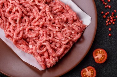 Siyah bir zemin üzerinde tuz ve baharatla doldurulmuş çiğ et ya da domuz eti.