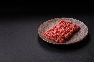 Siyah bir zemin üzerinde tuz ve baharatla doldurulmuş çiğ et ya da domuz eti.