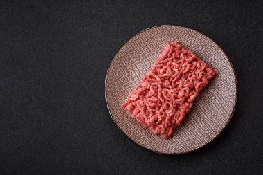 Siyah bir zemin üzerinde tuz ve baharatla doldurulmuş çiğ et ya da domuz eti.