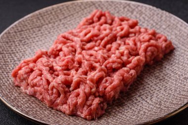 Siyah bir zemin üzerinde tuz ve baharatla doldurulmuş çiğ et ya da domuz eti.