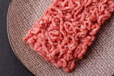 Siyah bir zemin üzerinde tuz ve baharatla doldurulmuş çiğ et ya da domuz eti.