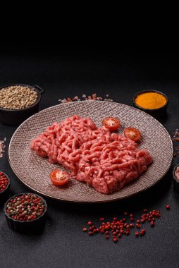 Siyah bir zemin üzerinde tuz ve baharatla doldurulmuş çiğ et ya da domuz eti.