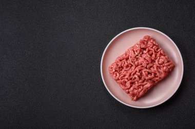 Siyah bir zemin üzerinde tuz ve baharatla doldurulmuş çiğ et ya da domuz eti.