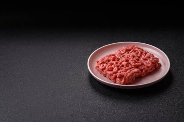 Siyah bir zemin üzerinde tuz ve baharatla doldurulmuş çiğ et ya da domuz eti.