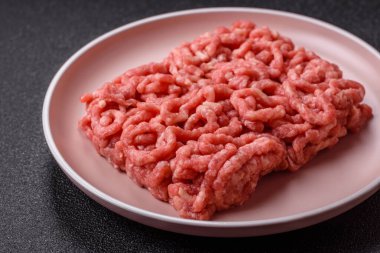 Siyah bir zemin üzerinde tuz ve baharatla doldurulmuş çiğ et ya da domuz eti.